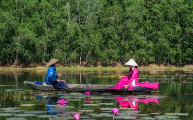 Binh Duong, Vietnam - 4 Şubat 2016. Asyalı kadın geleneksel elbise (Ao Dai) Nilüfer gölet ahşap teknede oturuyor.
