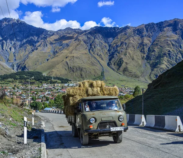 Um caminhão transportando grama na estrada da montanha — Fotografia de Stock