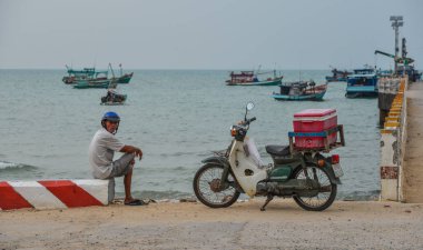 Kien Giang, Vietnam - 6 Nisan 2018. Kien Giang Nam Du Adası'nda balıkçılık iskelesinde motosiklet ile bir satıcı, Vietnam.