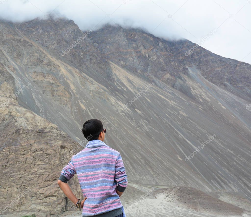 A young traveler looking at mountains in Ladakh, North of India.