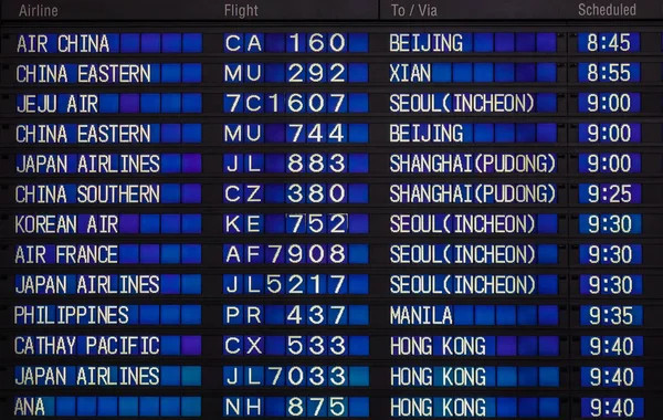 Airport board showing departures and arrivals to various cities.