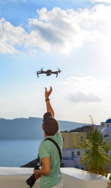 Santorini, Yunanistan - 4 Ekim 2018. Santorini, Yunanistan'daki Oia Town'da insansız hava aracı kullanan Asyalı bir gezgin.