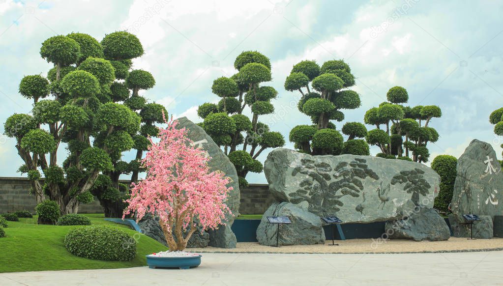 Typical Japanese garden - pine trees, lake, stone, grass and statue.