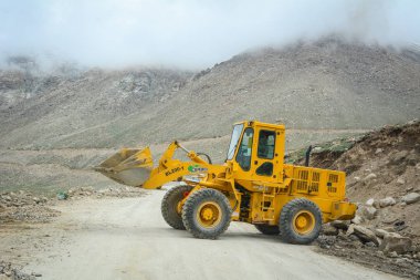 Ladakh, Hindistan - 18 Temmuz 2015. Ladakh, Hindistan'da dağ yolunda çalışan bir ekskavatör yükleyici makinesi.