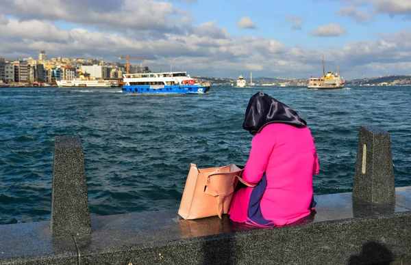 Ung muslimsk kvinne sitter på kaia – stockfoto