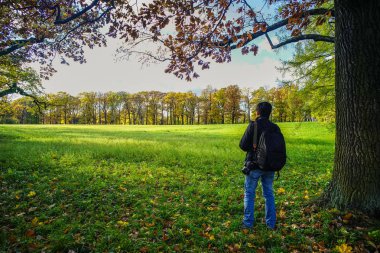 Yeşil bahçede duran Asyalı bir adam 