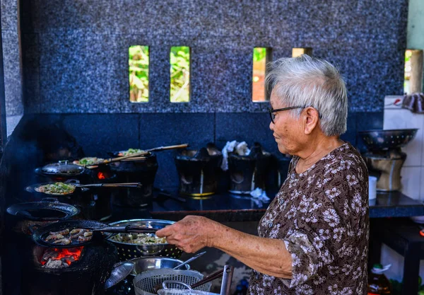 Una anciana cocinando panqueques tradicionales — Foto de Stock