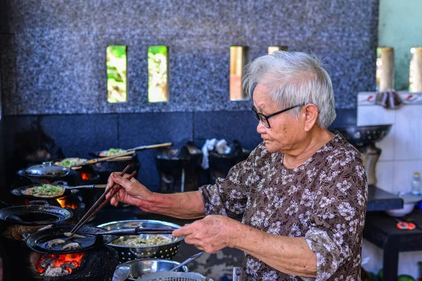 Una anciana cocinando panqueques tradicionales — Foto de Stock