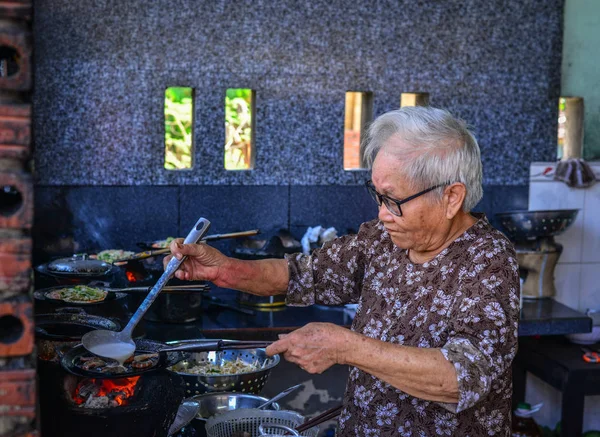 Una anciana cocinando panqueques tradicionales — Foto de Stock