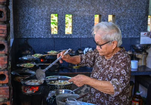 Una anciana cocinando panqueques tradicionales — Foto de Stock