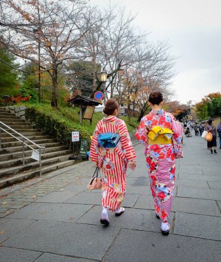 Kadınlar sokakta Japon kimonosu giyer. 
