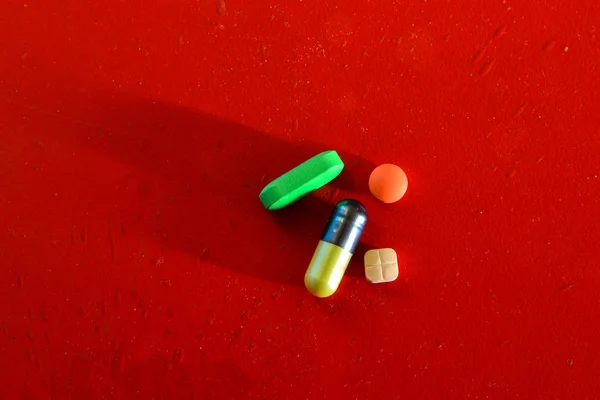 Medical or vitamin pills on red background