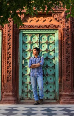 Ahşap kapıda duran genç bir adam. 