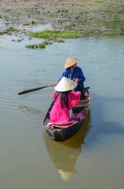 Binh Duong, Vietnam - 4 Şubat 2016. Asyalı kadın geleneksel elbise (Ao Dai) Nilüfer gölet ahşap teknede oturuyor.
