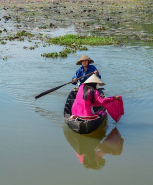 Binh Duong, Vietnam - 4 Şubat 2016. Asyalı kadın geleneksel elbise (Ao Dai) Nilüfer gölet ahşap teknede oturuyor.