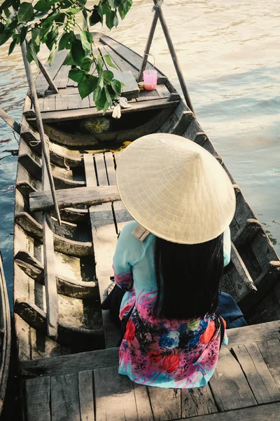 Woman sitting on the wooden boat at floating market in Can Tho, Vietnam.
