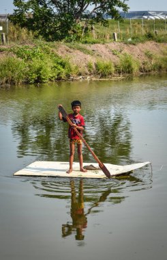 Zavallı bir çocuk kanalda kürek çekiyor. 