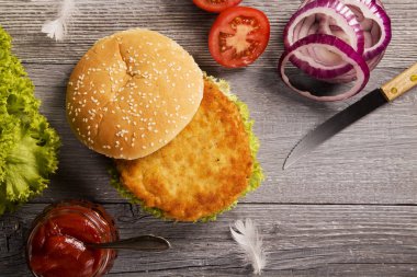 Ev yapımı tavuk burger marul, domates ve soğan ile