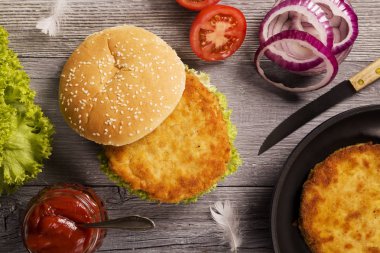 Ev yapımı tavuk burger marul, domates ve soğan ile