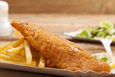Kızarmış balık ve cips bir kağıt tepsisi üzerinde