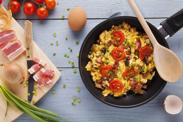 Πασπαλίζονται ανακατωμένα αυγά σε μια κατσαρόλα με το μπέικον, κρεμμύδι και ντομάτες — Φωτογραφία Αρχείου