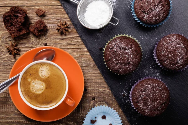 Chocolate muffins with icing sugar on a stone tray served with a — Stock Photo, Image