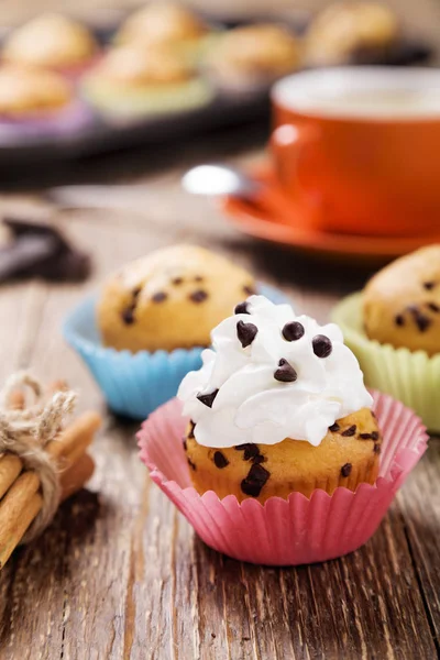 Muffins com chocolate em latas coloridas servidas com uma xícara de cof — Fotografia de Stock