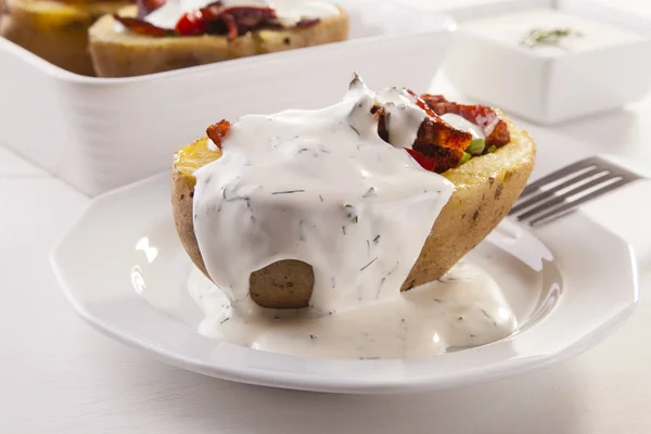 Baked potatoes stuffed with bacon served with dill sauce — Stock Photo, Image