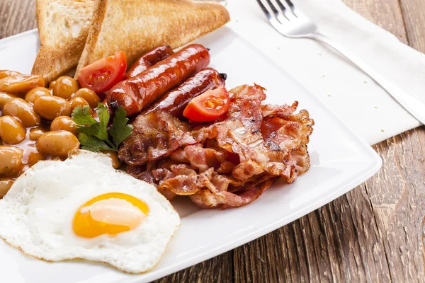 Kompletní anglická snídaně s slanina, klobása, sázené vejce, zapeč — Stock fotografie