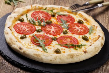 Pizza Vejetaryen taş siyah plaka üzerinde deneyin taze domates ve zeytin ile