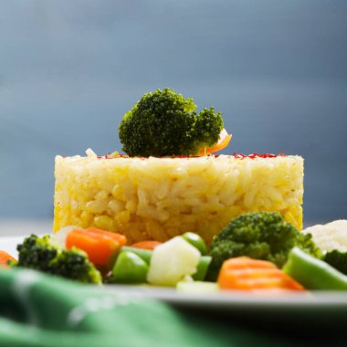 Sebzeli risotto kısmı. Beyaz tabakta.