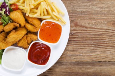 Nuggets ve bir plaka üzerinde fiş daldırma ve ahşap bir gemide salata ile servis