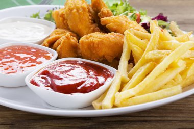 Nuggets ve bir plaka üzerinde fiş daldırma ve ahşap bir gemide salata ile servis