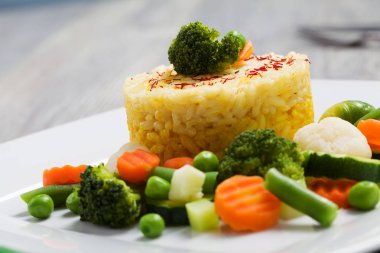 Sebzeli risotto kısmı. Beyaz tabakta.