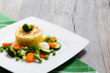 Sebzeli risotto kısmı. Beyaz tabakta.