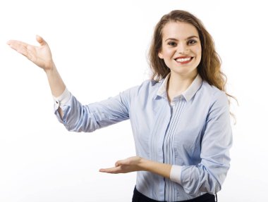 Güzel bir gülümseyen genç kadın portresi belirten bir jest olarak beyaz zemin üzerinde mavi bir gömlek giymiş