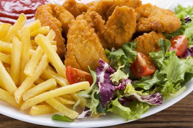 Nuggets ve bir plaka üzerinde fiş daldırma ve ahşap bir gemide salata ile servis