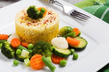 Sebzeli risotto kısmı. Beyaz tabakta.