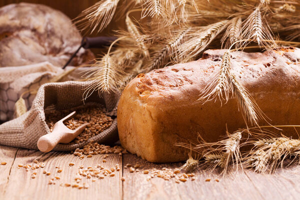 Состав свежего хлеба, круп и зерна на деревянной доске
.