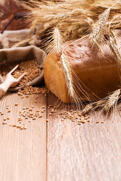 Composition of fresh bread, cereals and grains on wooden board.