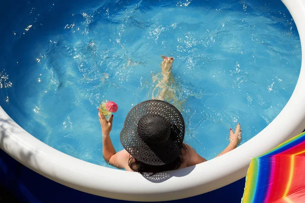 Young woman in a straw hat relaxing in the garden pool.