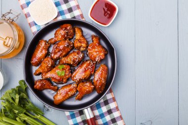 Fırında tavuk kanadı bal soslu susam serpilir.