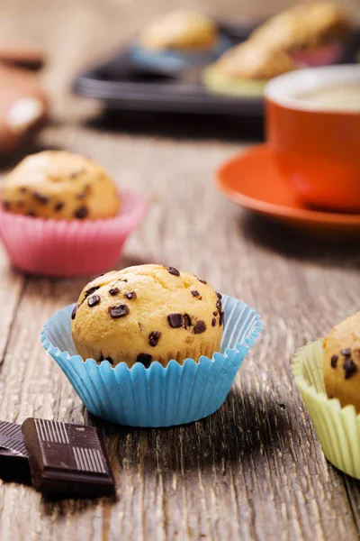 Muffins com chocolate em latas coloridas servidas com uma xícara de cof — Fotografia de Stock