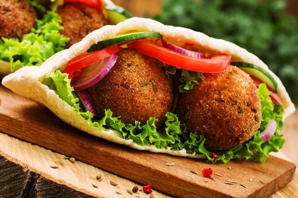 Falafel and fresh vegetables in pita bread on wooden table — Stock Photo, Image