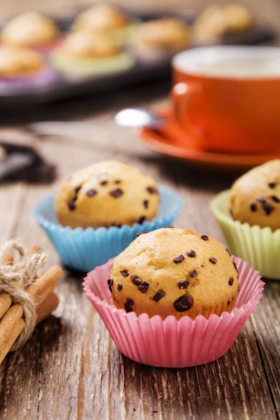 Muffins com chocolate em latas coloridas servidas com uma xícara de cof — Fotografia de Stock
