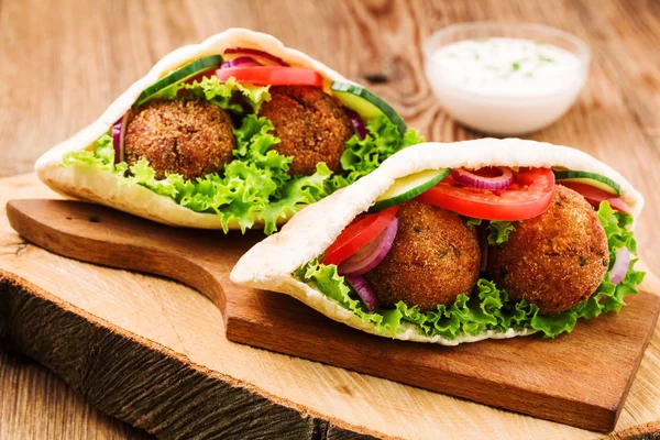 Falafel and fresh vegetables in pita bread on wooden table — Stock Photo, Image