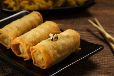 Siyah bir tabakta sebze ile pişmiş böreği