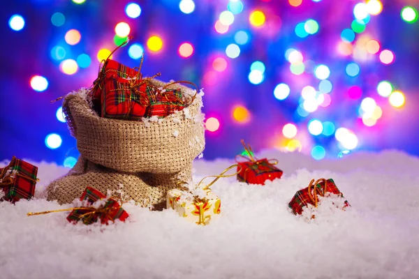 Sack Santa Claus with presents on snow, on a background of color — Stock Photo, Image