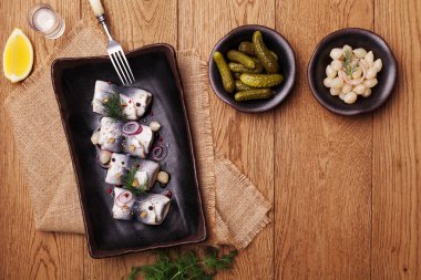 Sirke de haddelenmiş ringa, soğan ve turşu ile servis. 