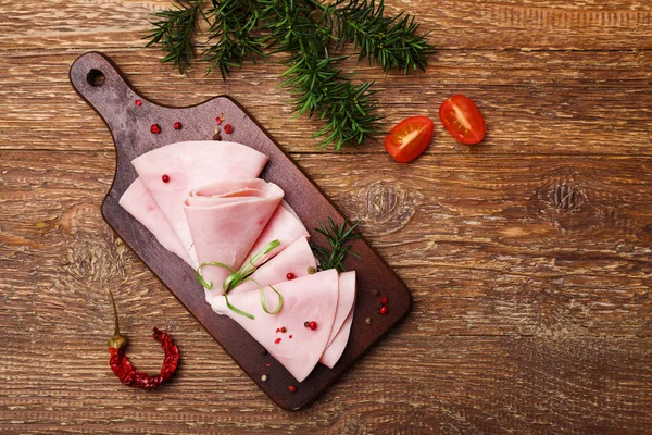 Delicious cooked ham on a wooden board with spices. — Stock Photo, Image